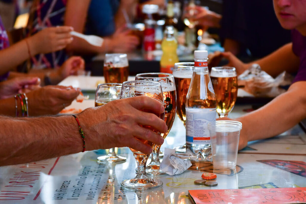 glasses of beer on a table in a bar, hands of people, a party with friends