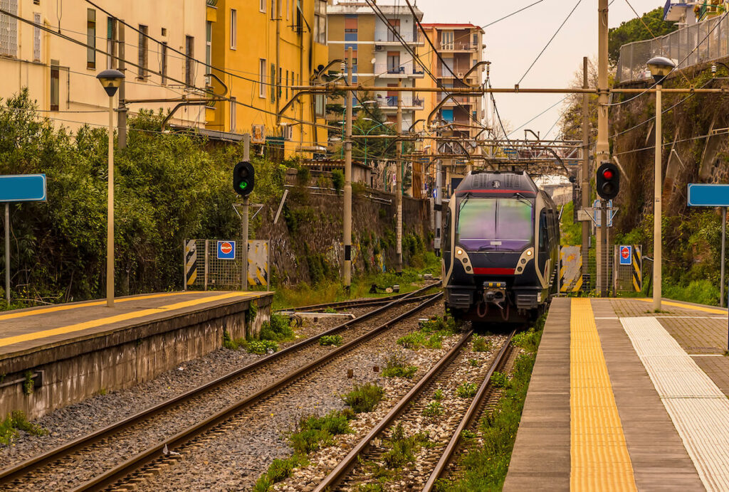 A view down a platform with a train approaching on the railway line between Naples and Sorrento, Italy