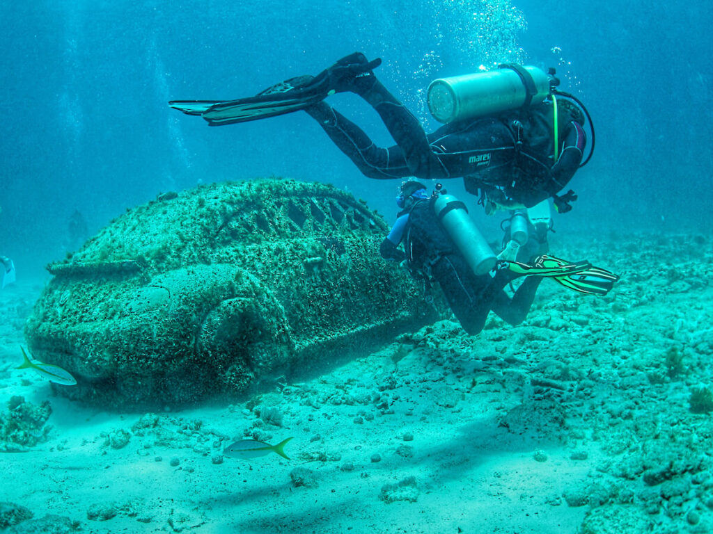 divers swim by artwork at Cancun’s underwater museum