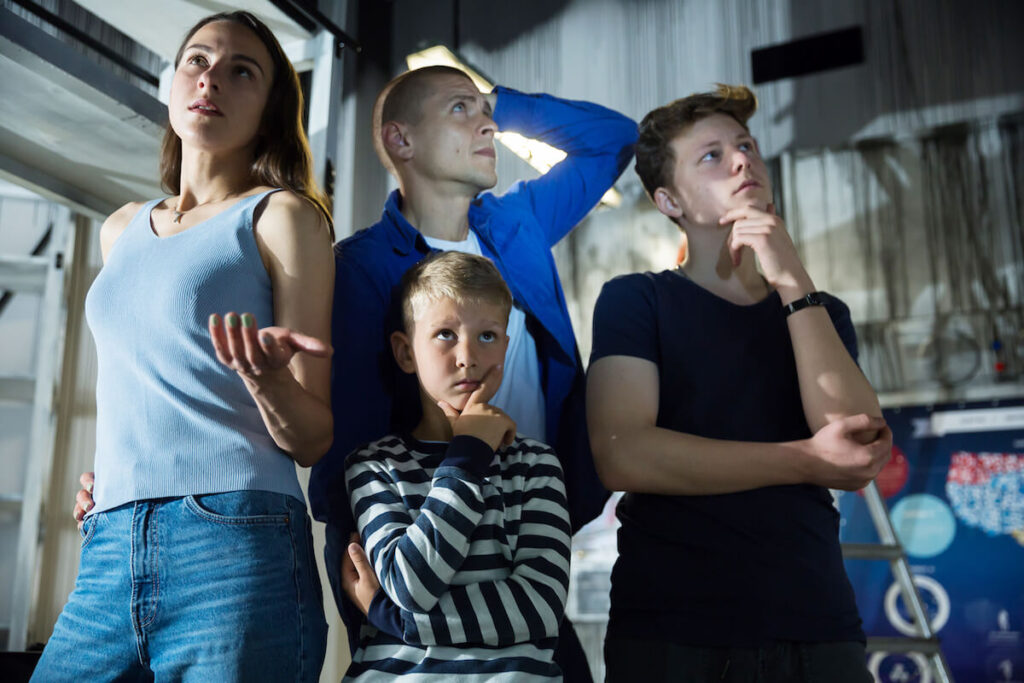 Two interested teen boys with their parents trying to get out of closed space of escape room