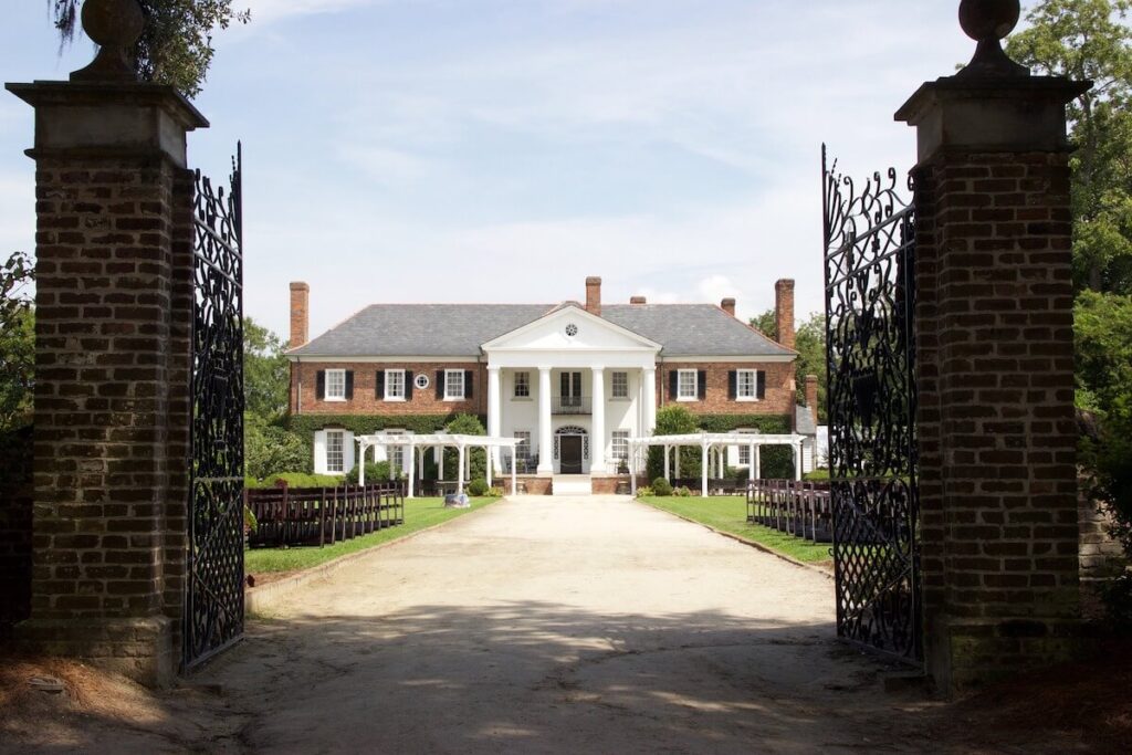 Gates open to pillared mansion