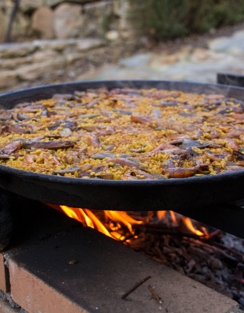 Spanish Paella cooked on natural log fire and coal in a traditional fireplace
