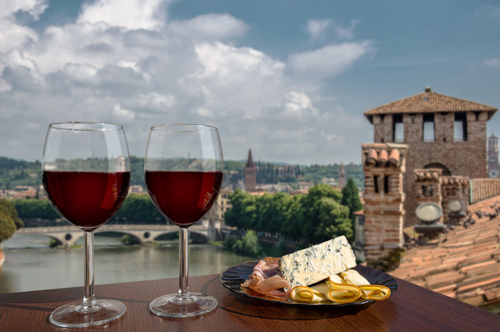 Two glasses of wine and charcuterie assortment with a view of Verona, Italy