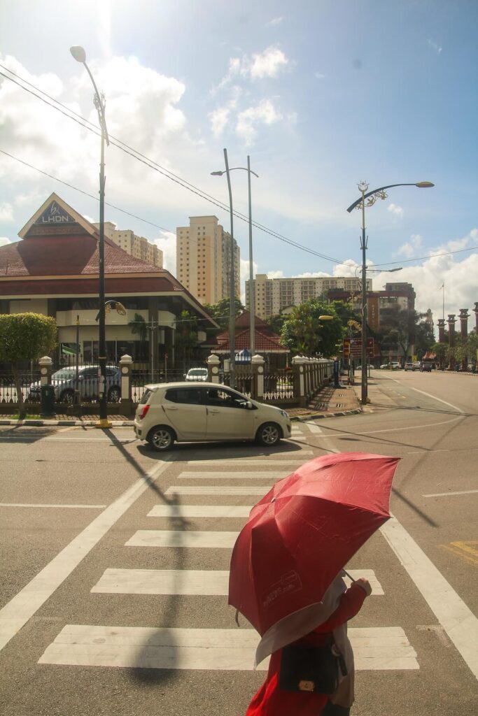 person with a red umbrella crossing a street