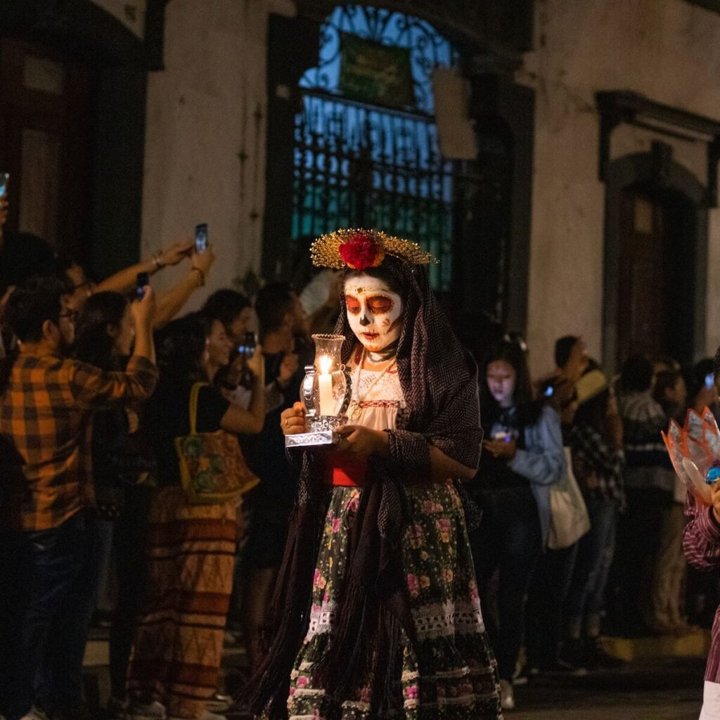 Woman with sugar skull face lit with candle