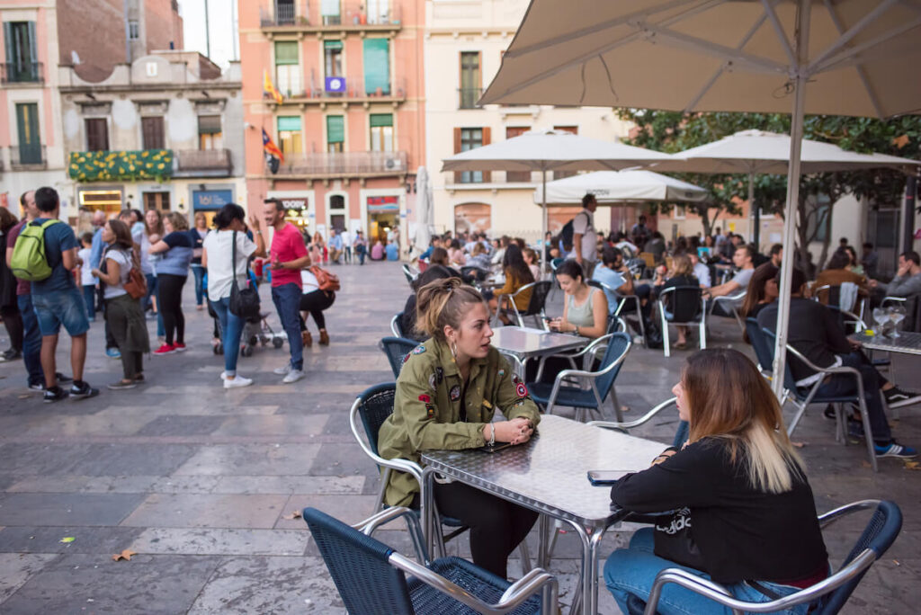 young friends waiting to eat in the Gracia neighborhood, in the Plaza Revelucio