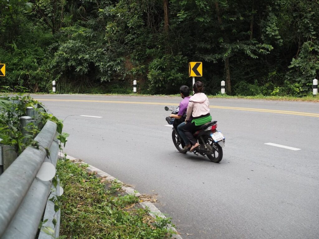 Motorcycle scooter with rider and pillion passenger going around a corner on the road to Doi Suthep