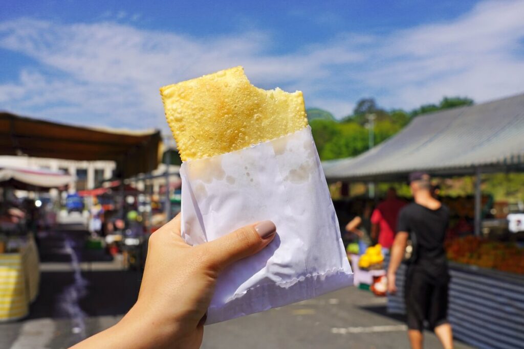 Pastel de Feira, Brazilian stuffed fried pastry against market fair in Sao Paulo, Brazil