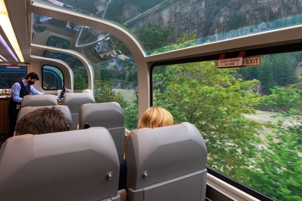 Passengers in the Rocky Mountaineer gold leaf 360 degrees panoramic train wagon along Fraser River, British Columbia, Canada