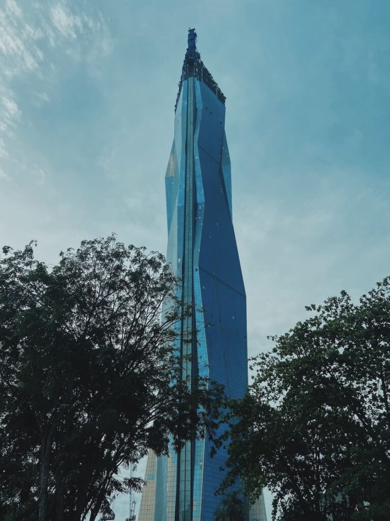 Merdeka 118 towering over a forest of trees