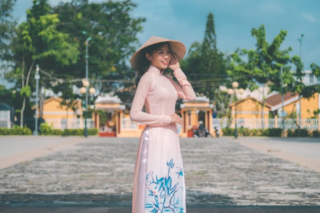 smiling woman wearing Ao Dai and Vietnamese hat