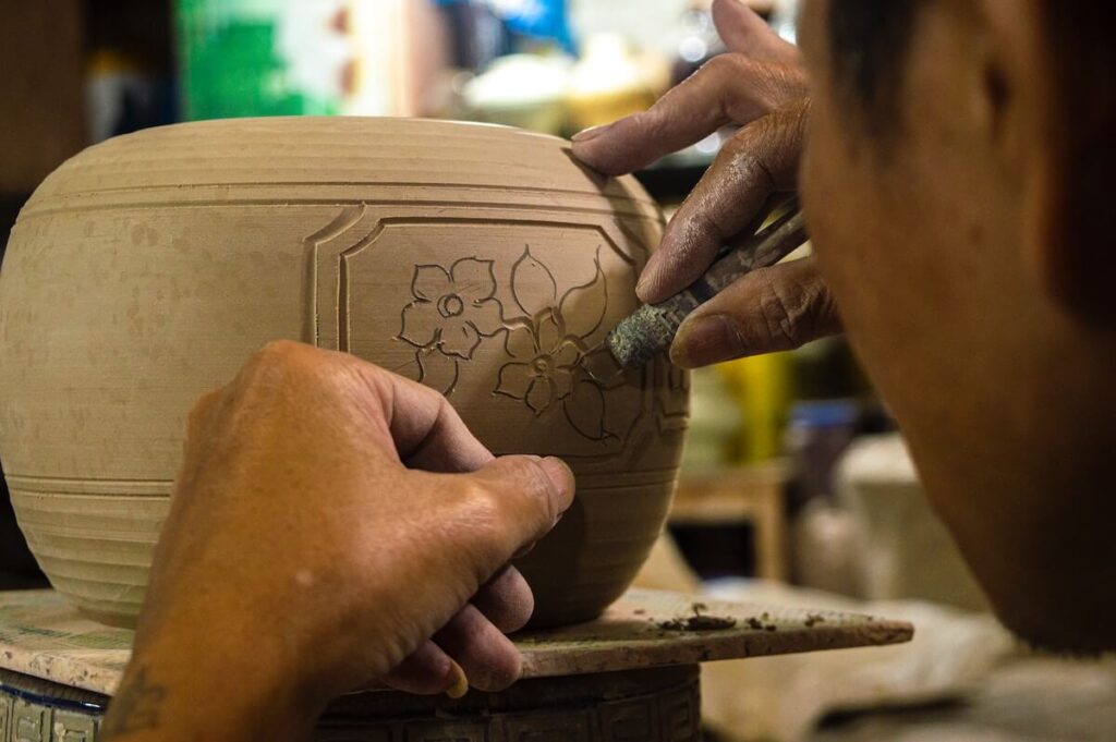 man carving design in ceramic