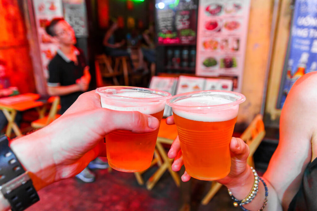 two people toasting cups of Hanoi beer