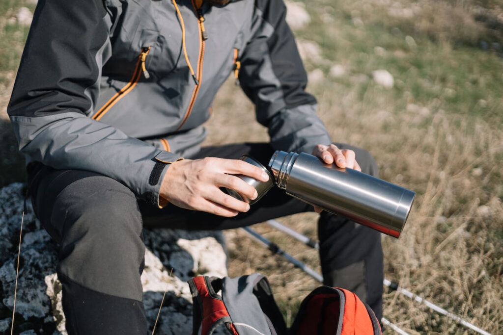 Man’s hands holding thermos and pouring drink