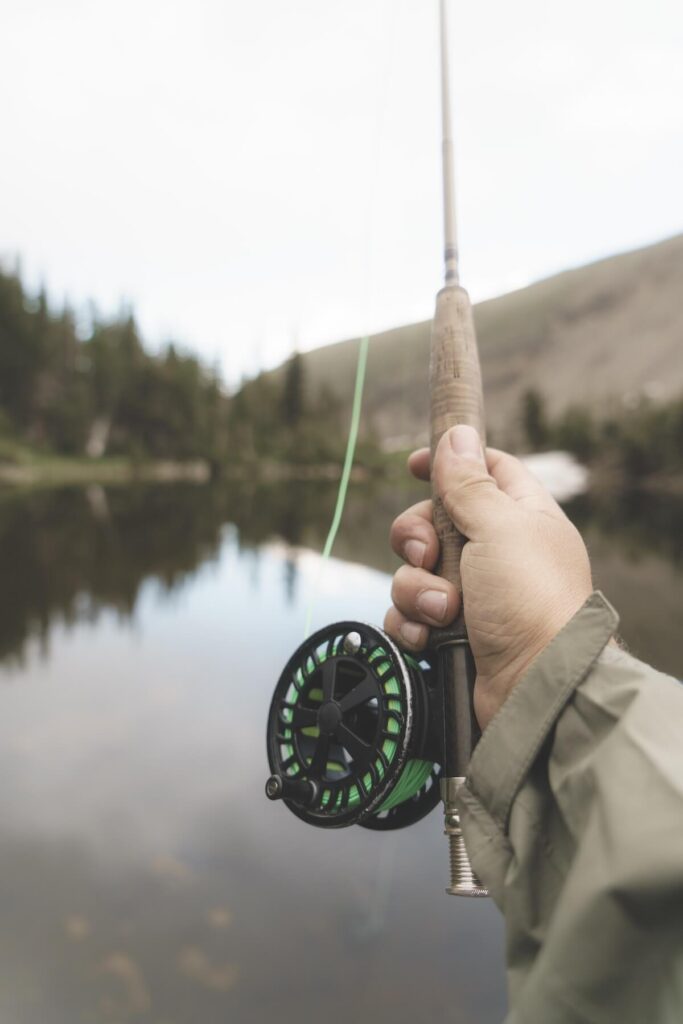 Person holding fishing reel against mountain river in Nederland
