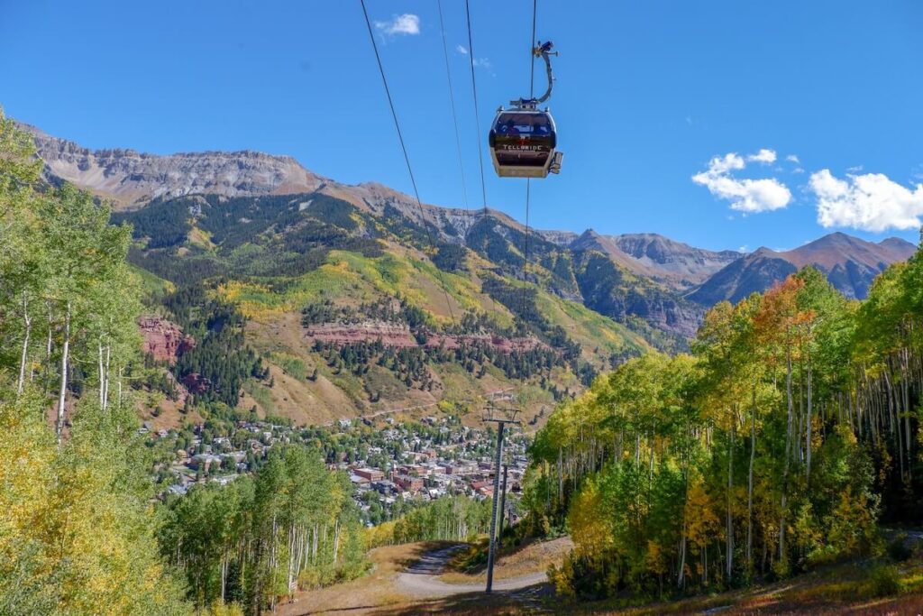 view of cable car over green trees and mountain in Telluride