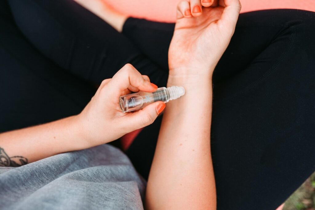 woman using roll-on bottle of essential oil
