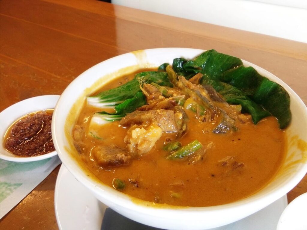 bowl of kare-kare with bagoong on the side