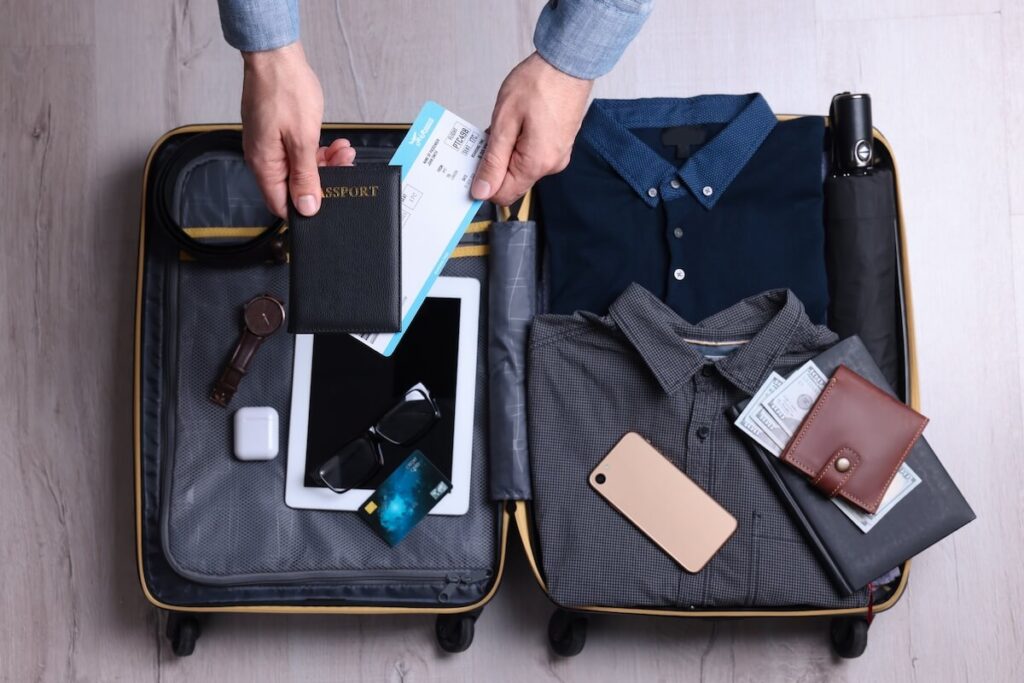 man packing suitcase with assorted items