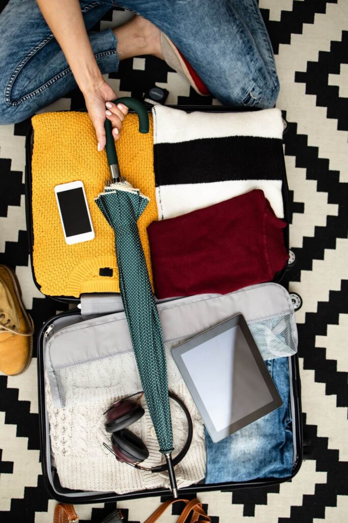 woman packing suitcase with assorted items