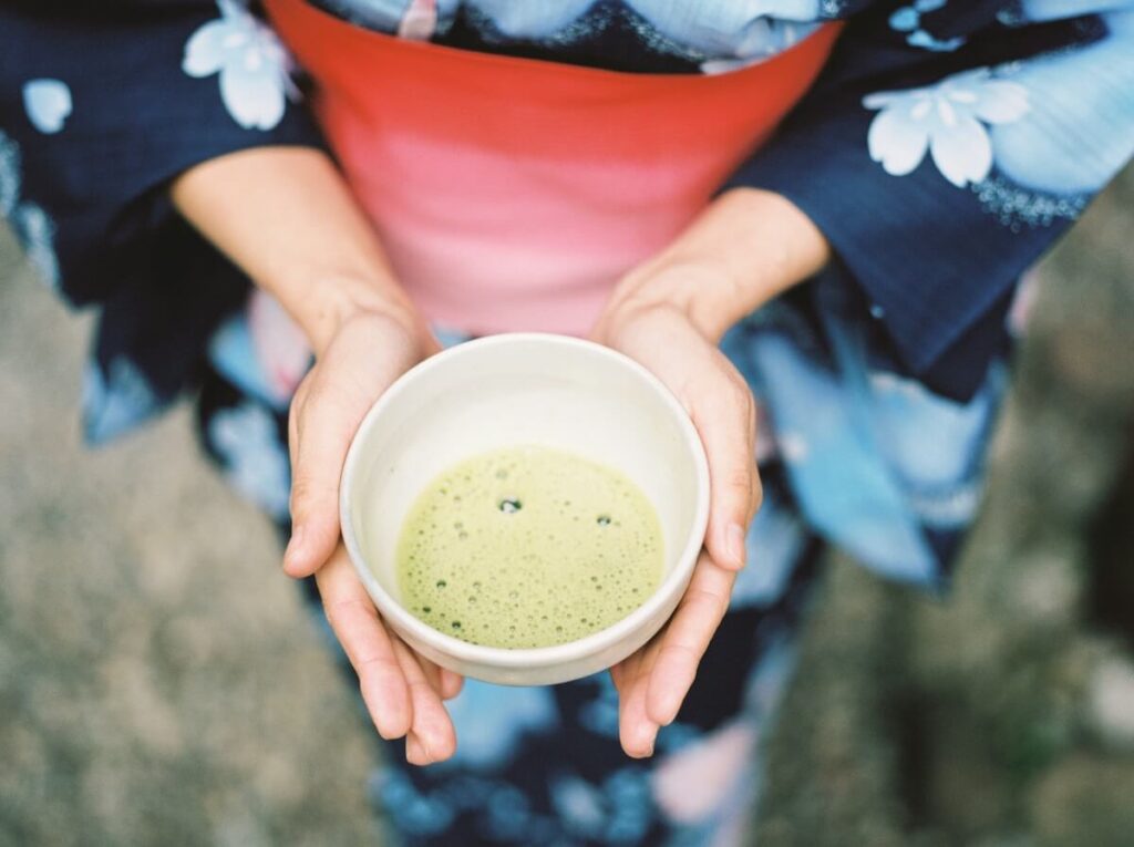 woman wearing kimono and holding bowl of matcha
