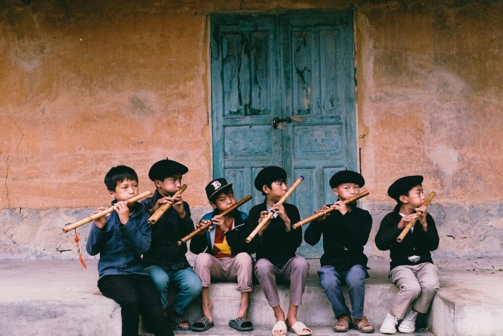 Vietnamese boys playing bamboo flutes
