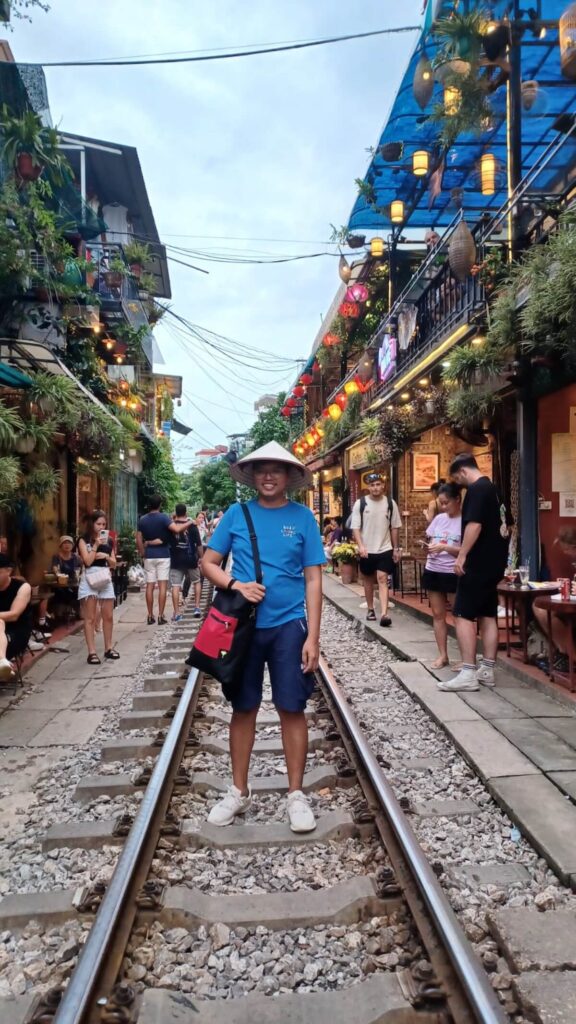 man wearing non la, standing in Hanoi Train Street