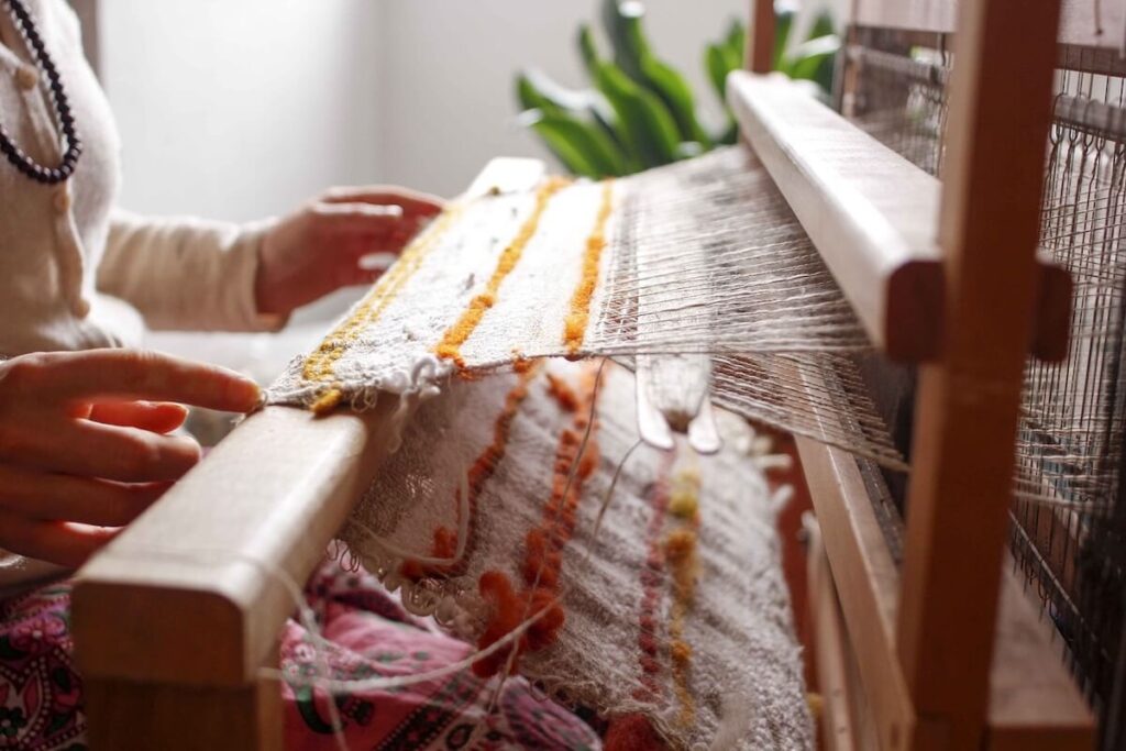 woman weaving cloth on loom