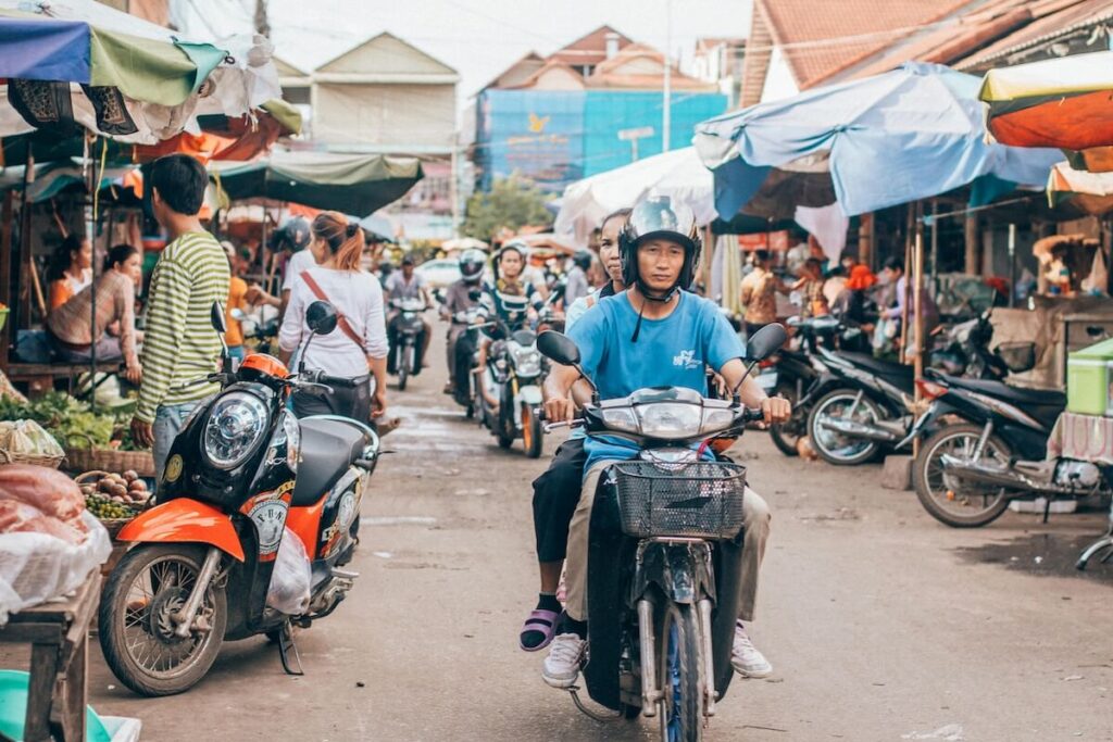 motorcycles passing by busy market in Siem Reap
