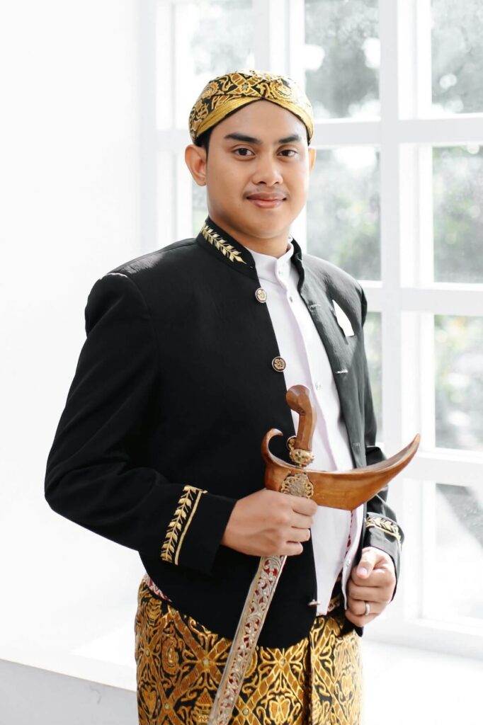 man wearing traditional Indonesian attire and clutching a Kris, Indonesian dagger