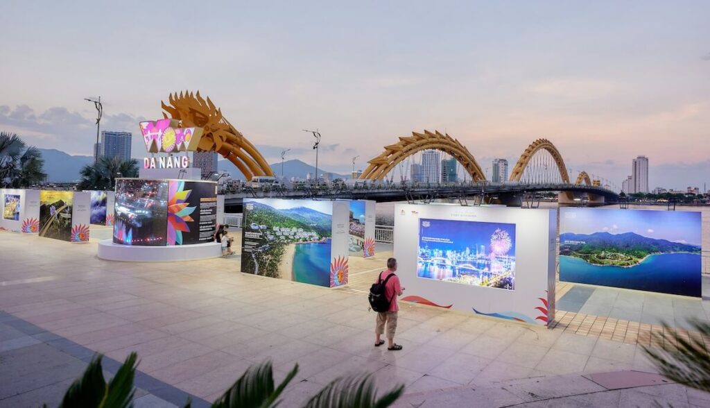 man looking at outdoor gallery in Da Nang, with the Dragon Bridge in the background