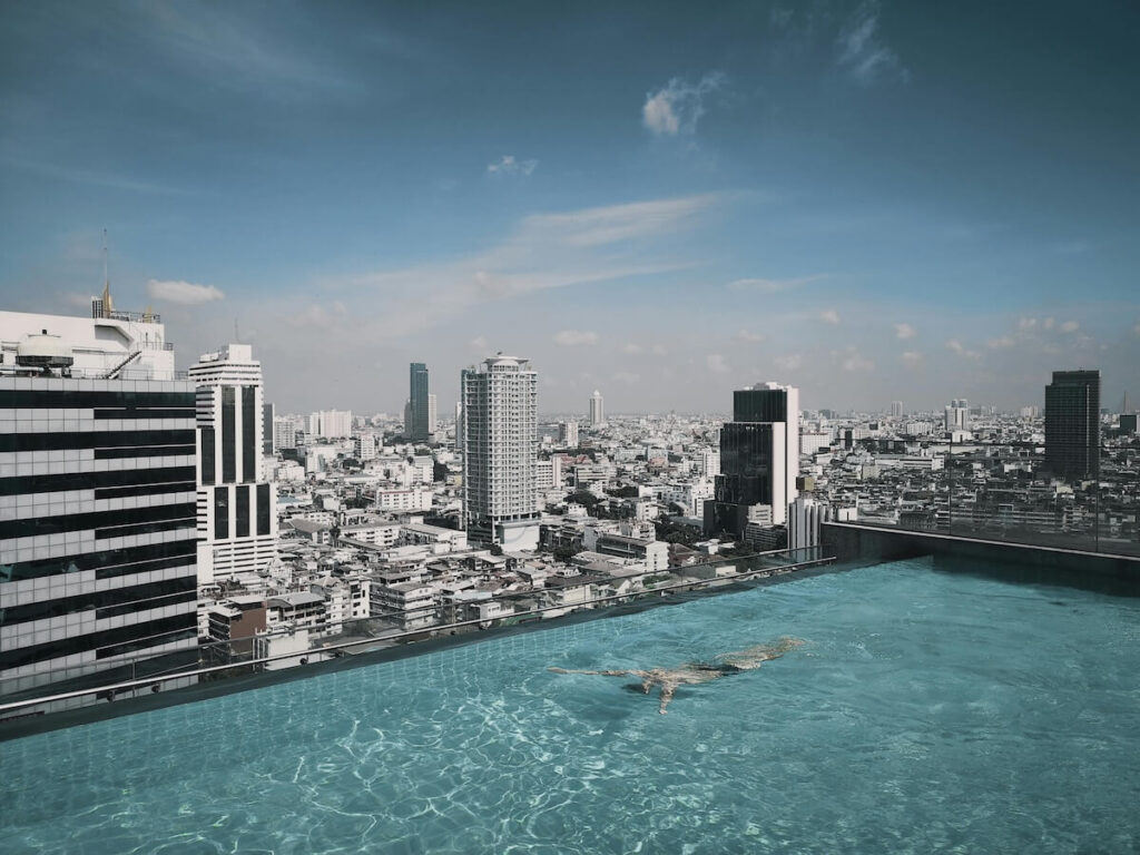 man swimming in rooftop pool on a Bangkok hotel