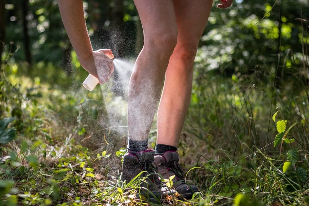 woman spraying insect repellent on legs