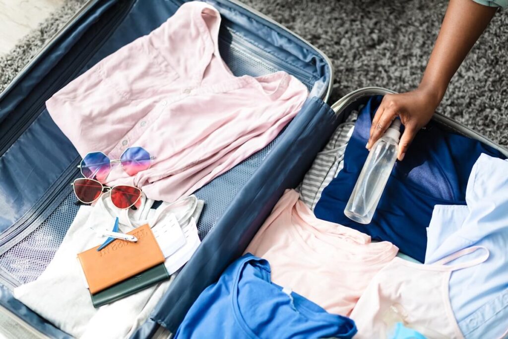 person putting spray bottle on luggage