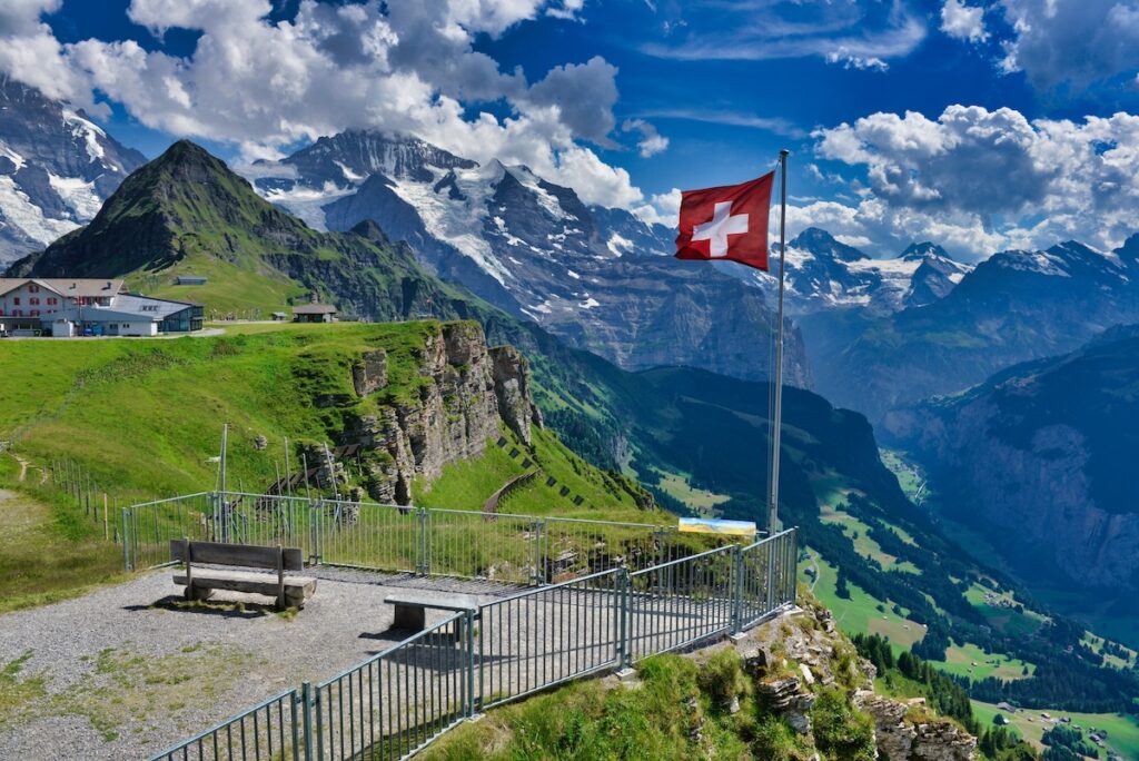 Swiss flag flying over Grindelwald in Bern, with view of the Alps