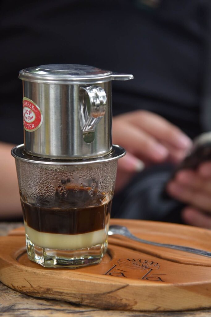 focus on glass of Vietnamese coffee with phin on top of glass