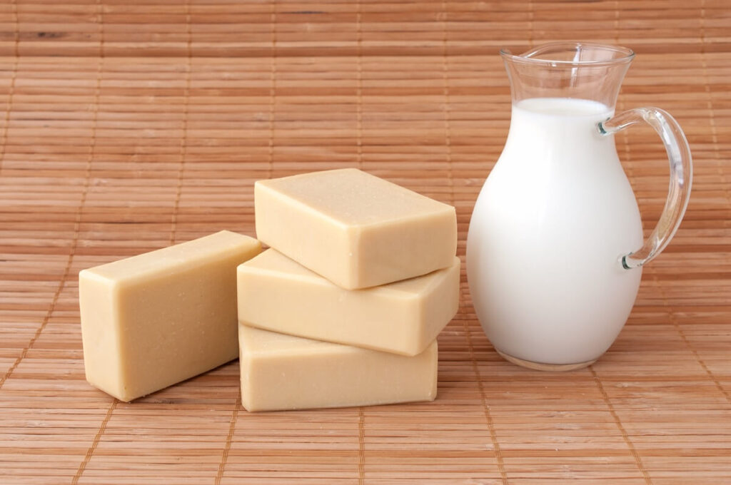 bottle of goat milk and bars of soap