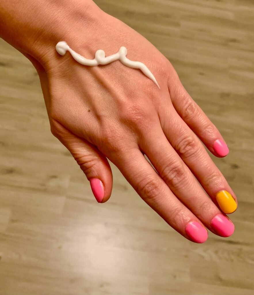 hands with colorful nails and hand cream on it