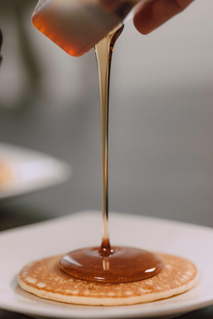 pouring maple syrup on pancake
