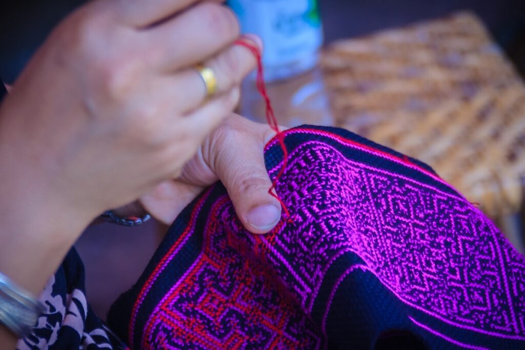 woman weaving paj ntaub