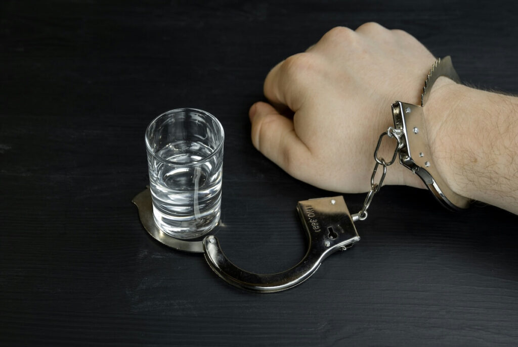 man with hand cuff and glass of alcohol