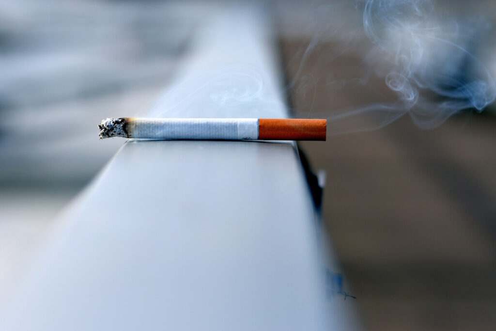 closeup of lit cigarette on a railing