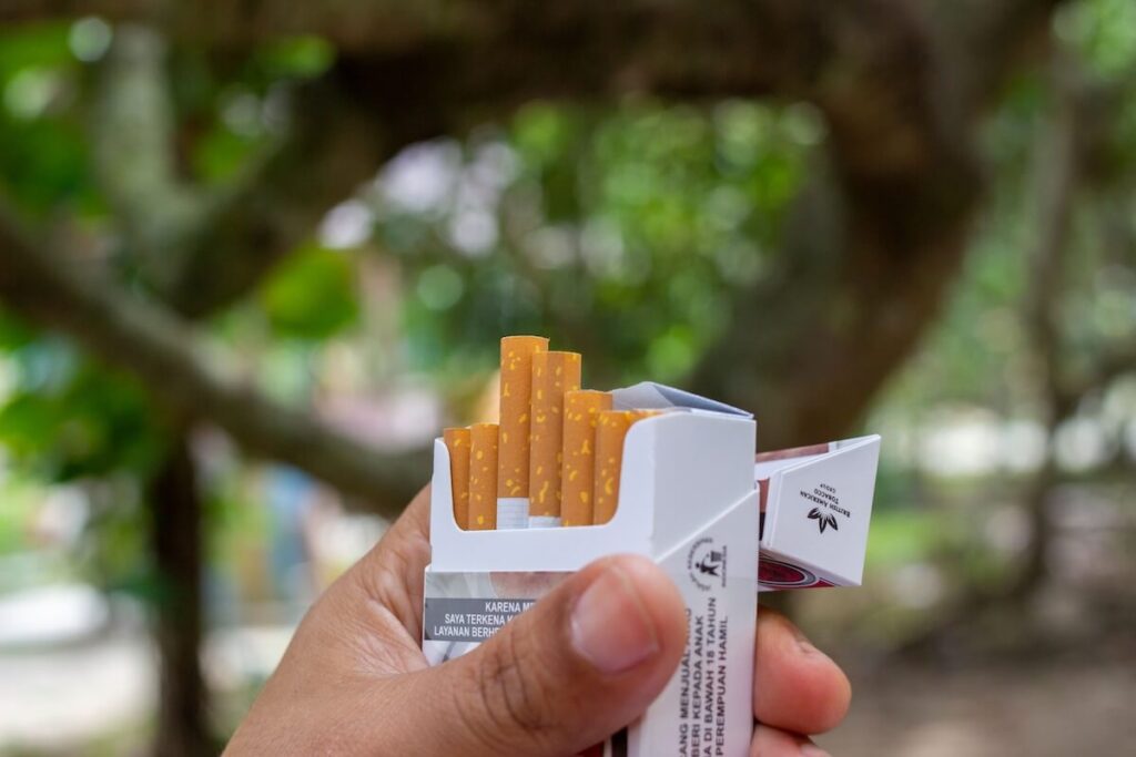 hand holding open pack of cigarette outdoors