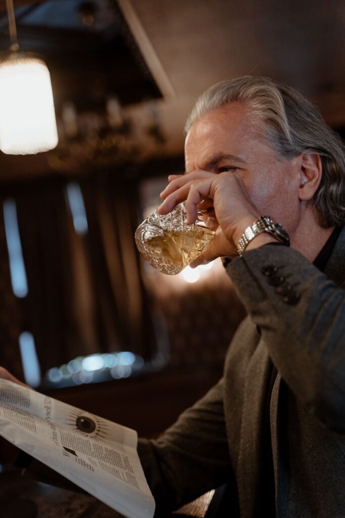 old man drinking with paper in hand