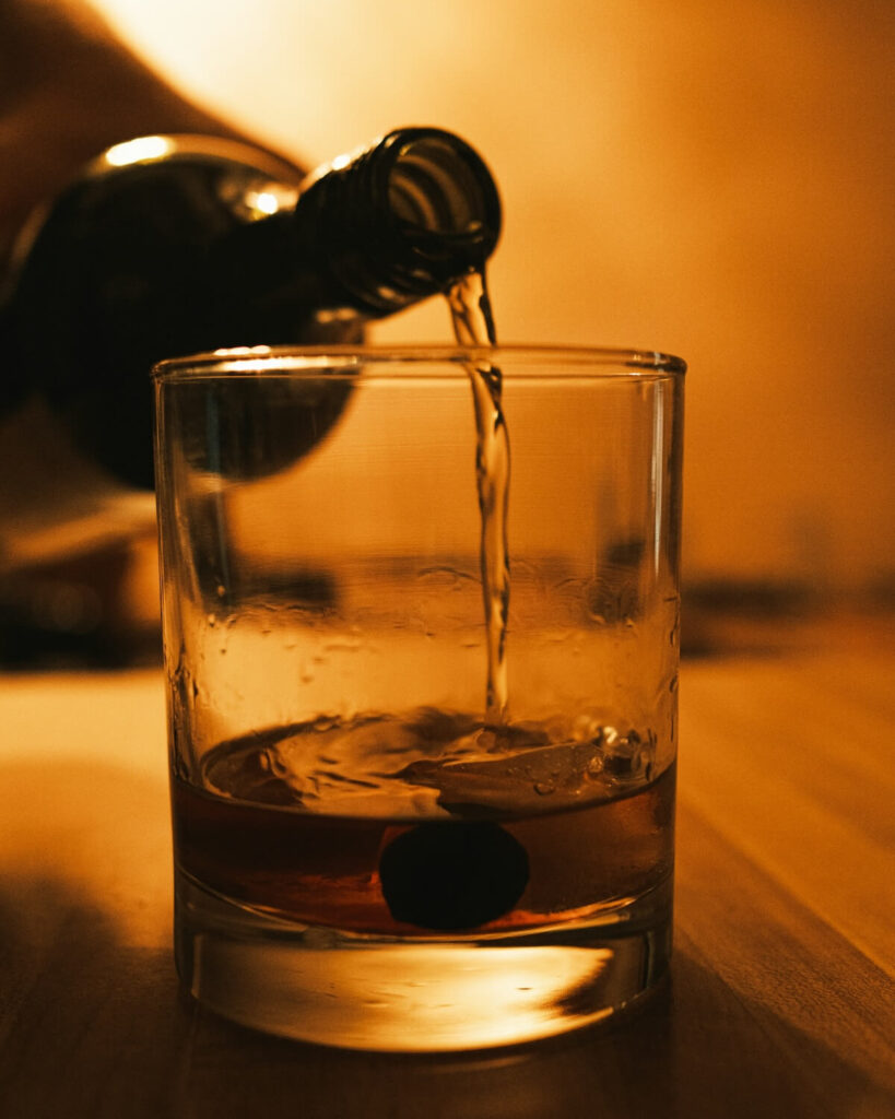man pouring drink on glass
